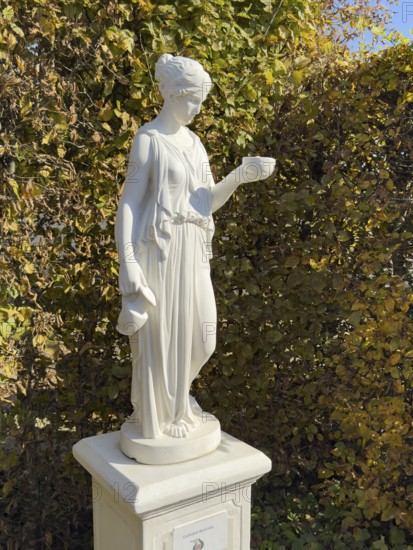Statue of in Greek mythology goddess of youth Hebe Roman goddess Iuventas of male youth holding a sacrificial bowl in the garden of the open-air museum archaeological park Römische Villa Borg, Perl, Saarland, Germany