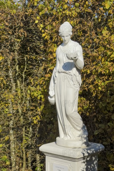 Statue of in Greek mythology goddess of youth Hebe Roman goddess Iuventas of male youth holding a sacrificial bowl in the garden of the open-air museum archaeological park Römische Villa Borg, Perl, Saarland, Germany