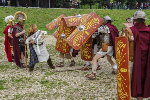 Traditional group Roman soldiers and centurion centurion in the tradition of historic ancient Roman battle group foot troop with sword and shield plays depicts attack by Germanic Celtic warriors on military turtle formation, Circus Maximus, Rome, Italy
