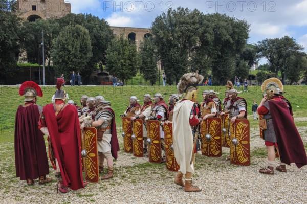 Traditional group Roman soldiers and centurion centurion in tradition of historic ancient Roman Roman formation of battle group foot troop with sword and shield, in the background part of the ruin of the palace of Emperor Domitian Domitian, Circus Maximus, Rome, Italy