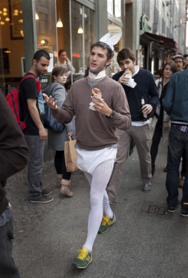 DEU Berlin tourist in bunny costume and doner kebab on Rosenthaler Straße in Berlin Mitte. He's having his bachelor party. Germany Berlin tourist wearing a bunny costums strolls along Rosenthaler Straße in Berlin Mitte