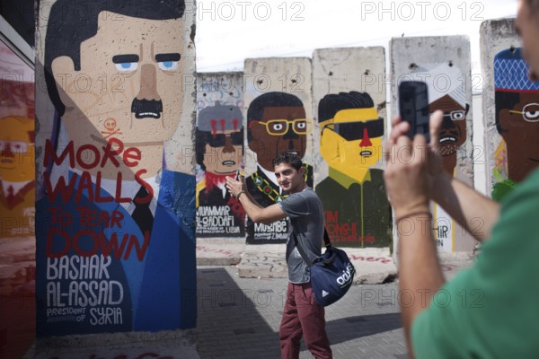DEU Germany Germany Berlin A tourist has himself photographed shooting in front of Syrian dictator Bashar Al-Assad