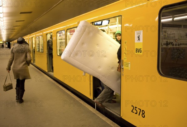 DEU Germany Berlin traveler with mattress boards the U 9 towards Osloer Straße in the Spichernstraße station Germany Berlin A passenger is entering the tube with a mattress in his hand