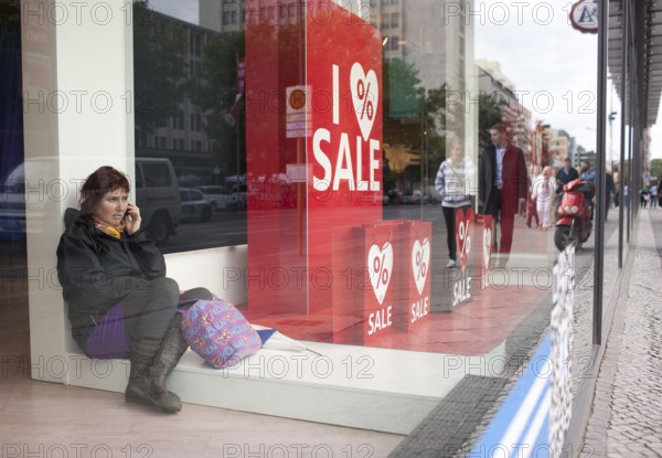 DEU Germany Germany Berlin Woman talking on the phone in a shop window on Kurfürstendamm in Berlin