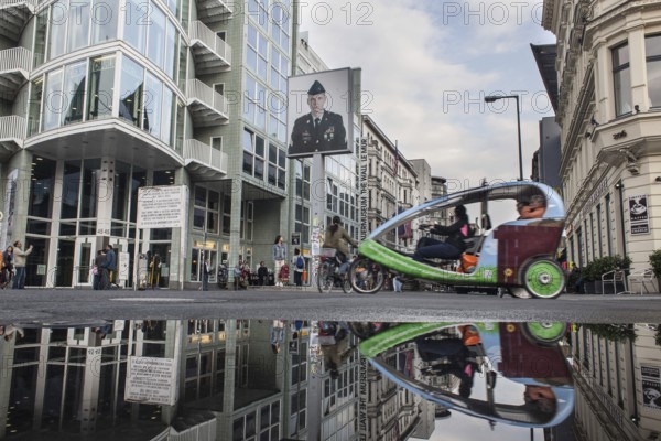 DEU Germany Germany Berlin Tourists at Checkpoint Charlie reflecting in a puddle after rain