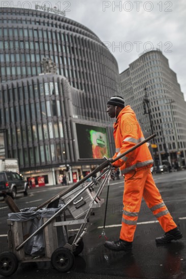 DEU Germany Berlin An employee of Stadtreinigung BSR pushes his handcart across a block of Kurfürstendamm. Germany Berlin A public service worker crosses the street in the center of West Berlin