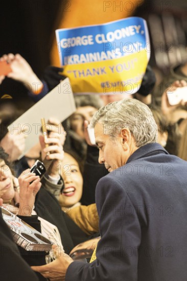 DEU Germany Germany Berlin 64th Berlinale, the international film festival in the German capital. The director of the films 'Monuments Men' George Clooney signs autographs. In the background, a banner on which Ukraine thanks him for his commitment
