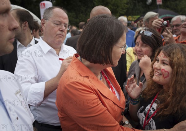 DEU, Germany, Berlin, 17.08.2013 SPD election campaign kick-off with top candidate Peer Steinbrück under the slogan “The We Decide” with a celebration of 150 years of the SPD in front of the Brandenburg Gate in Berlin. Sign autographs on Mrs. Gertrud Steinbrück's back. 150 years anniversay party of the German social democratic party in front of the upcoming general election with candidate Peer Steinrück