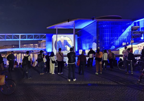Passers-by watch the projection To the German People — A Parliamentary Search for Clues at the Marie-Elisabeth-Lüders House of the Bundestag in Berlin, Germany