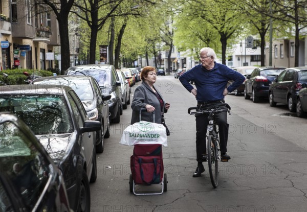 DEU Germany Germany Berlin Neighborhood conversation between an elderly woman with shopping cart and a cyclist on Regensburger Straße in Schöneberg