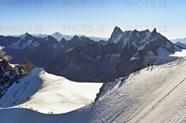Mountaineers climb over a snow-covered mountain ridge, behind Grandes Jorasses, viewing platform, mountain station, Aiguille du Midi, Chamonix-Mont-Blanc, Haute-Savoie, France
