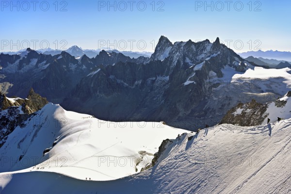 Mountaineers climb over a snow-covered mountain ridge, behind Grandes Jorasses, viewing platform, mountain station, Aiguille du Midi, Chamonix-Mont-Blanc, Haute-Savoie, France