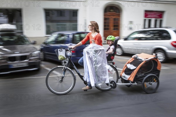 DEU Germany Germany Berlin female cyclist with children holding ironed shirts while riding