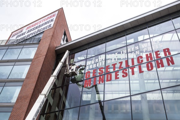 DEU Germany Germany Berlin Window cleaner on the façade of the Verdi headquarters, where an unconditional minimum wage is advertised