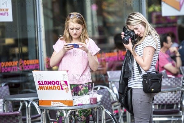 DEU Germany Germany Berlin Girls photograph a box of donuts they just bought in front of a Dunkin Donut movie at Potsdamer Platz