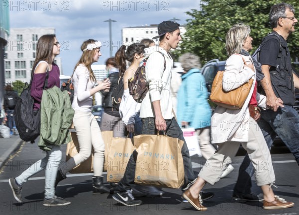 DEU Germany Germany Berlin Young people walk across a pedestrian crossing at Potsdamer Platz with Primark shopping bags