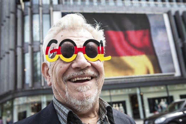 DEU Germany Germany Berlin Passers-by in front of a projection screen on Kurfürstendamm, on which a commercial featuring a large German flag is being broadcast