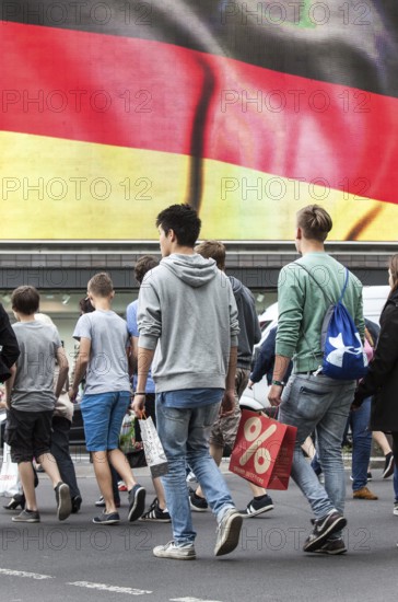 DEU Germany Germany Berlin Passers-by in front of a projection screen on Kurfürstendamm, on which a commercial featuring a large German flag is being broadcast