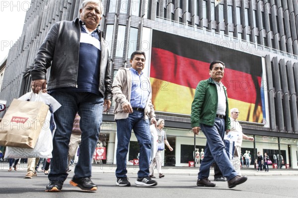 DEU Germany Germany Berlin Passers-by in front of a projection screen on Kurfürstendamm, on which a commercial featuring a large German flag is being broadcast