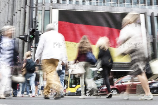 DEU Germany Germany Berlin Passers-by in front of a projection screen on Kurfürstendamm, on which a commercial featuring a large German flag is being broadcast