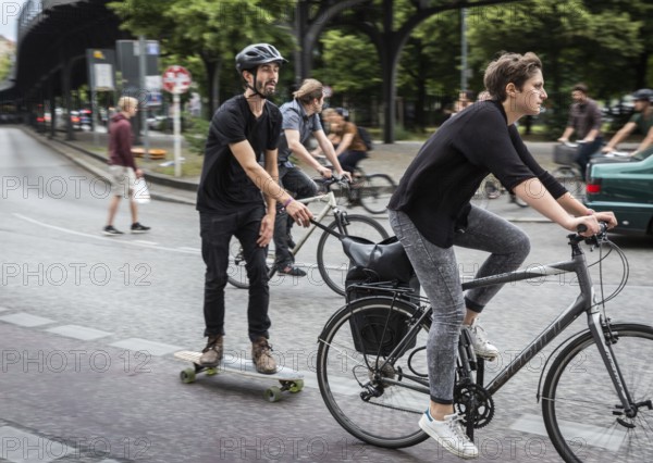 DEU Germany Germany Berlin female cyclist pulls skateboarders on Skalitzer Straße in Kreuzberg