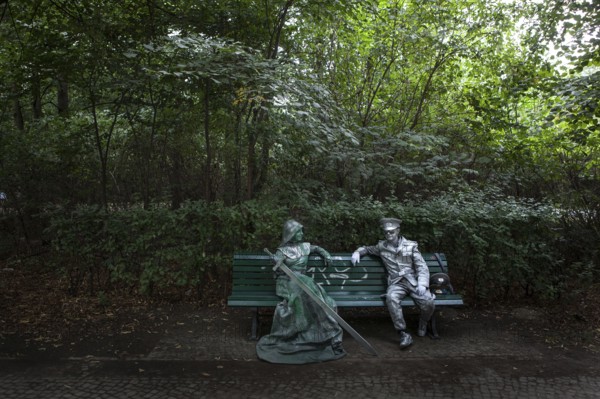 DEU Germany Germany Berlin Two performers take a break on a bench between the Reichstag and the Brandenburg Gate. The two earn their money as living statues