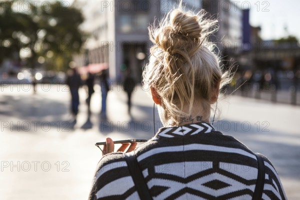 DEU Germany Germany Berlin Woman holds her smartphone while she is telephoning across the square at the memorial church