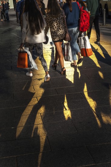 DEU Germany Germany Berlin Passers-by cast their shadow on Berlin's popular shopping street, Tauentzien. The gold of a glass façade is reflected on the sidewalk