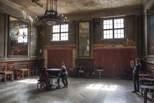 DEU Germany Germany Berlin Visitor films two woman playing a piano in the Hall of Mirrors at Clärchen's Ballhaus in Mitte
