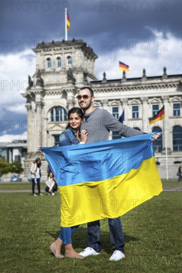 DEU Germany Germany Berlin Urcainian tourists take pictures of themselves with their national flag in front of the Reichstag