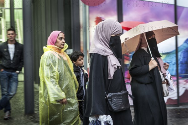 DEU Germany Germany Berlin Women wearing headscarves and face veils walking through the rain on Tauentzien