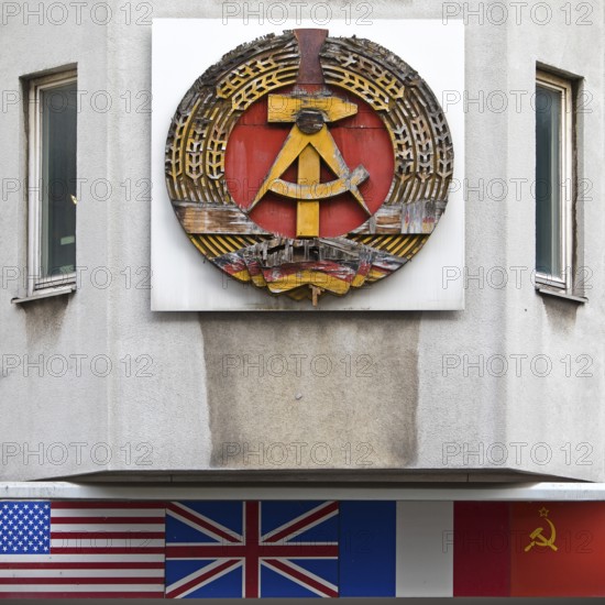 Old building of the Wall Museum — Museum Haus am Checkpoint Charlie with the old coat of arms of the GDR and the flags of the occupying powers, Berlin, Germany
