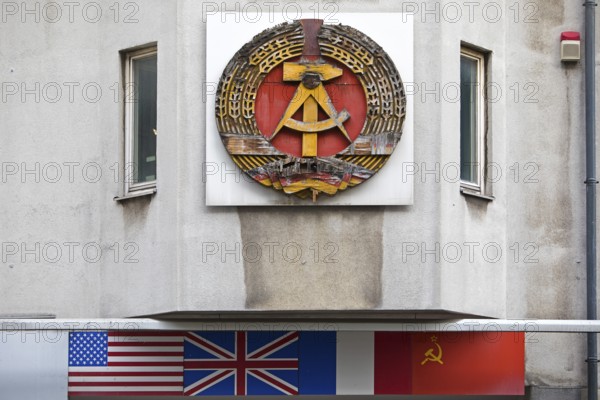 Old building of the Wall Museum — Museum Haus am Checkpoint Charlie with the old coat of arms of the GDR and the flags of the occupying powers, Berlin, Germany