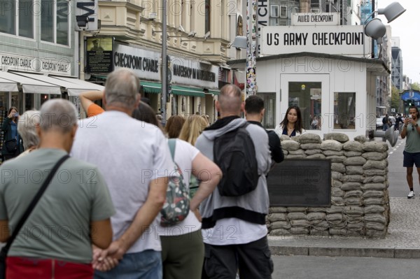 Tourists at Checkpoint Charlie queue for a souvenir photo, Berlin, Germany