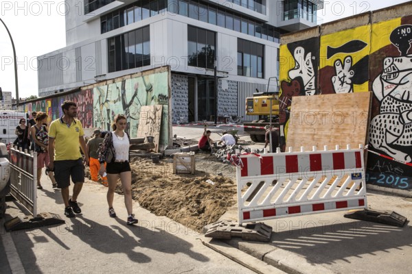 DEU Germany Germany Berlin Tourists pass through the opening in the East-Side Gallery, which was built for a new building. The removal of the piece of wall for the construction of the luxury property directly on the Spree behind the wall led to fierce protests among the population