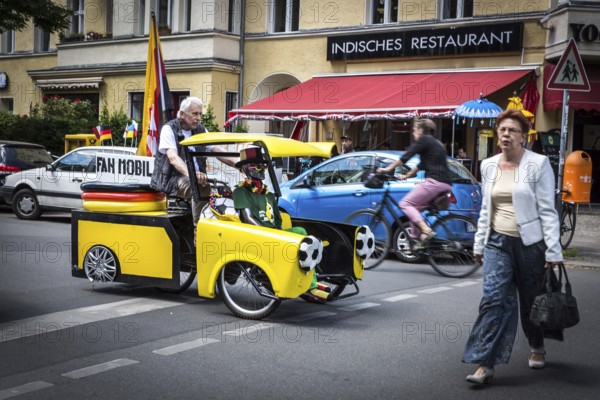 DEU Germany Germany Berlin A man drives through Schöneberg in a self-made European championship fanmobile, a bicycle rickshaw. The van can be rented