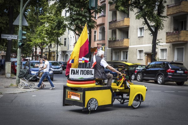 DEU Germany Germany Berlin A man drives through Schöneberg in a self-made European championship fanmobile, a bicycle rickshaw. The van can be rented