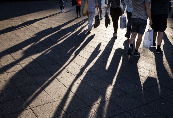 DEU Germany Germany Berlin People with shopping bags cast their shadows on the sidewalk of the cow dam