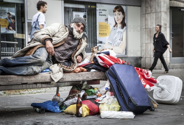 DEU Germany Germany Berlin A homeless person sits on a bench next to his belongings in a square in Schöneberg