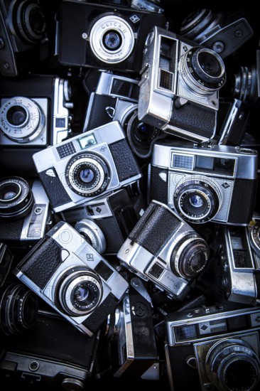 DEU Germany Germany Berlin Analog viewfinder cameras are on display by a salesman at the flea market in front of Schöneberg City Hall. Since the predominance of digital cameras, the predecessors to be equipped with film can be purchased very cheaply
