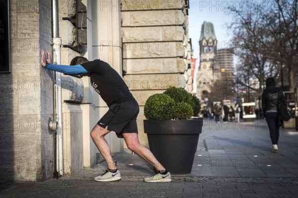 DEU Germany Germany Berlin A jogger does gymnastics in front of an Apple shop display case on Kudamm
