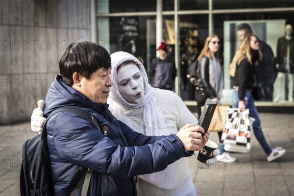 DEU Germany Germany Berlin A tourist takes a selfie with a white-painted woman on the Kudamm. The woman talks to passers-by about money