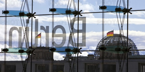 View from the main train station with the inverted Berlin lettering on the glass façade and the Reichstag with German flags, Berlin, Germany