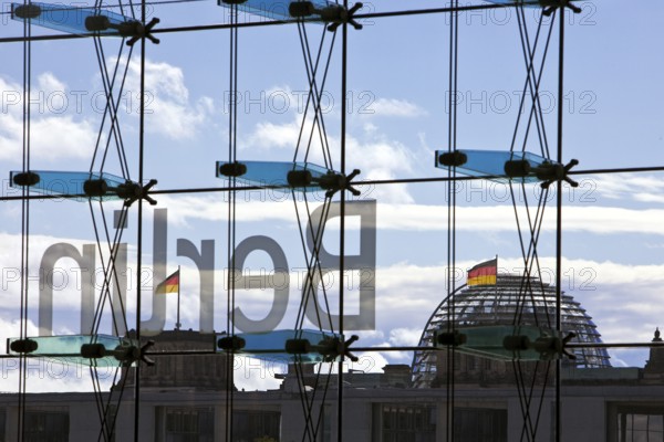 View from the main train station with the inverted Berlin lettering on the glass façade and the Reichstag with German flags, Berlin, Germany