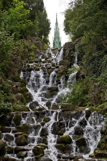 Artificial waterfall in Victoria Park, with the national monument on Kreuzberg in the background, Berlin-Kreuzberg, Germany