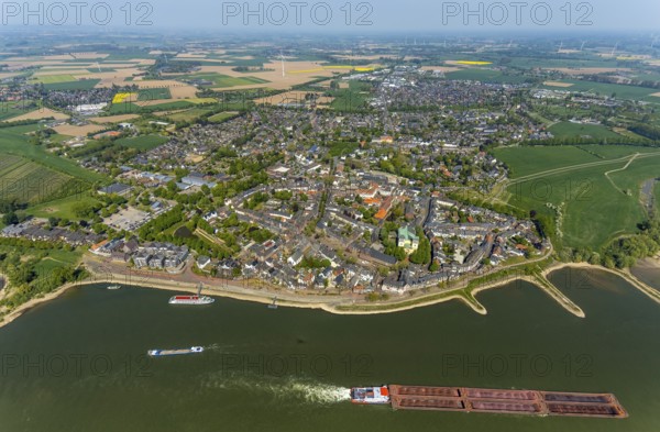 Aerial view, town view Rees, river Rhine, catholic church St. Mariä Himmelfahrt, Rheinterrassen Rees, Rhine promenade, shipping, Rees, Lower Rhine, North Rhine-Westphalia, Germany, excursion boat, DE, Europe, distant view, property tax, real estate, Kalkar, cargo ships, aerial view, aerial photography, aerial photography, shipping pier, shipping traffic, overview, bird's eye view, meadows and fields, residential area, living and life, residential area, residential buildings, residential quality, housing estate, birds-eyes view, overview