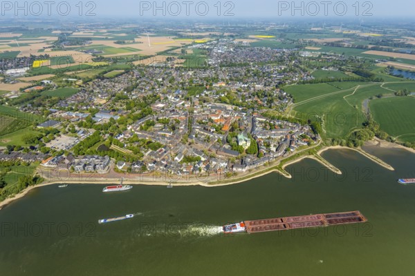Aerial view, town view Rees, river Rhine, catholic church St. Mariä Himmelfahrt, Rheinterrassen Rees, Rhine promenade, shipping, Rees, Lower Rhine, North Rhine-Westphalia, Germany, excursion boat, DE, Europe, distant view, property tax, real estate, Kalkar, cargo ships, aerial view, aerial photography, aerial photography, shipping pier, shipping traffic, overview, bird's eye view, meadows and fields, residential area, living and life, residential area, residential buildings, residential quality, housing estate, birds-eyes view, overview