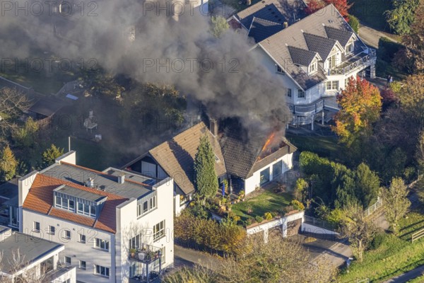 Several callers reported a fire with heavy smoke on Bergerstraße in Mülheim-Menden at 2.57 pm today, Saturday. When the first emergency services arrived, they discovered that the roof truss of a two-storey residential building was fully engulfed in flames. Due to the expected long and intensive operation, a full alarm was immediately sounded for the volunteer fire brigade. There were no residents in the house. Firefighters from the professional fire brigade immediately began fighting the fire from the inside and using a turntable ladder. As the operation progressed, they were supported by colleagues from the Heißen fire brigade of the volunteer fire brigade. Once the actual fire had been extinguished, the post-extinguishing work proved to be quite complex and lengthy. Parts of the roof have to be removed in order to reach any remaining embers. The ongoing operation involved two fire engines, several special and command vehicles from the professional fire brigade as well as vehicles fro...