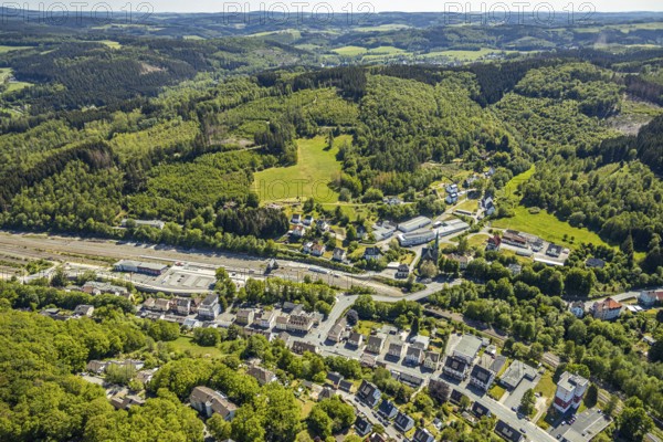 Aerial view, Brügge district, Lüdenscheid-Brügge railway station, Lüdenscheid fire brigade, Brügge equipment depot, Evang. Kreuzkirche Brügge, Lüdenscheid, Märkischer Kreis, Sauerland, North Rhine-Westphalia, Germany, place of worship, railway tracks, railway station, station forecourt, fire fighter, fire protection, fire station, bridge signal box, federal road B54, DE, Deutsche Bahn AG, Europe, distant view, fire engine, fire brigade, fire station, fire engine, commercial area, commercial use, religious community, place of worship, property tax, green trees, hilly landscape, real estate, church, parish, denomination, district town, aerial view, aerial photography, aerial photography, fire engine, tenement houses, religion, separation station, overview, bird's eye view, Volmetalbahn, meadows and fields, living and life, residential buildings, birds-eyes view, green lung, overview