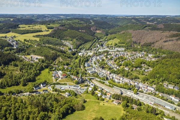 Aerial view, Brügge district, Lüdenscheid-Brügge railway station, Lüdenscheid fire brigade, Brügge equipment depot, Evang. Kreuzkirche Brügge, Lüdenscheid, Märkischer Kreis, Sauerland, North Rhine-Westphalia, Germany, place of worship, railway tracks, railway station, station forecourt, fire fighter, fire protection, fire station, bridge signal box, federal road B54, DE, Deutsche Bahn AG, Europe, distant view, fire engine, fire brigade, fire station, fire engine, commercial area, commercial use, religious community, place of worship, property tax, green trees, hilly landscape, real estate, church, parish, denomination, district town, aerial view, aerial photography, aerial photography, fire engine, tenement houses, religion, separation station, overview, bird's eye view, Volmetalbahn, meadows and fields, living and life, residential buildings, birds-eyes view, green lung, overview